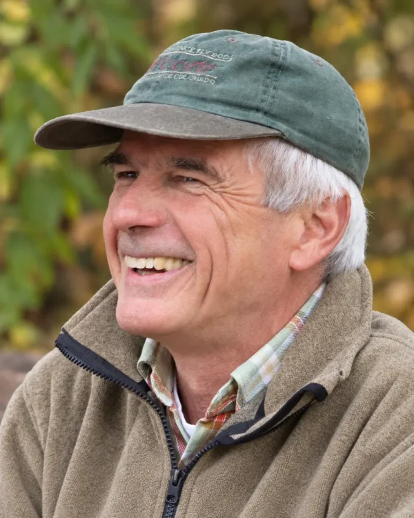Wolfgang Peham lächelt mit grüner Kappe im Freien.